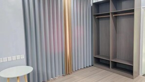 Een kamer met een grote kast, een witte tafel en een gordijn als scheiding.