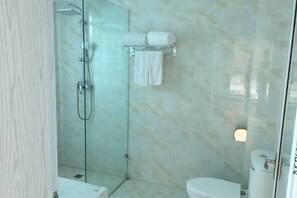 Une salle de bain avec une douche à parois de verre, des toilettes et un porte-serviettes avec deux serviettes.