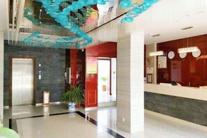 Eine Hotelhalle mit einer Rezeption, einer Pflanze und einer Treppe.