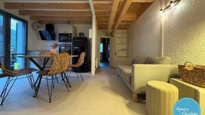 A modern kitchen with a dining area, a sofa, and a small ottoman. - The Bergerie T3- view Mountains. (Talloires-Montmin)