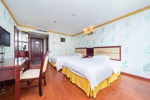 Two single beds with white bedding and yellow skirts, a desk with a chair, and a television are featured in this traditional room.