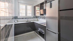 A modern kitchen with a stainless steel refrigerator, a built-in oven, and a window with a view of the outside. - Torero II Apartment - Marchena (Marchena)