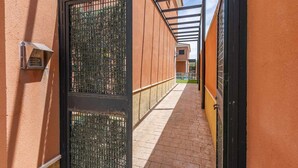 A narrow corridor with a metal gate, a brick pathway, and a building with orange walls. - Torero II Apartment - Marchena (Marchena)