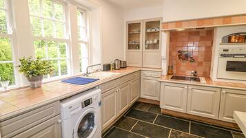 A kitchen with a washing machine, a sink, cabinets, and a tiled backsplash.
