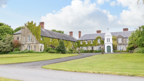 A large estate with multiple buildings, a well-maintained lawn, and a paved driveway. - Scarvagh House (Craigavon)