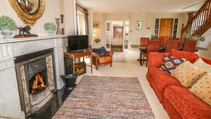 A living room with a fireplace, a television, a sofa, and a dining area. - Scarvagh House (Craigavon)