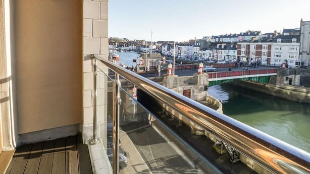 Un balcon donnant sur un port, des bâtiments et un pont.