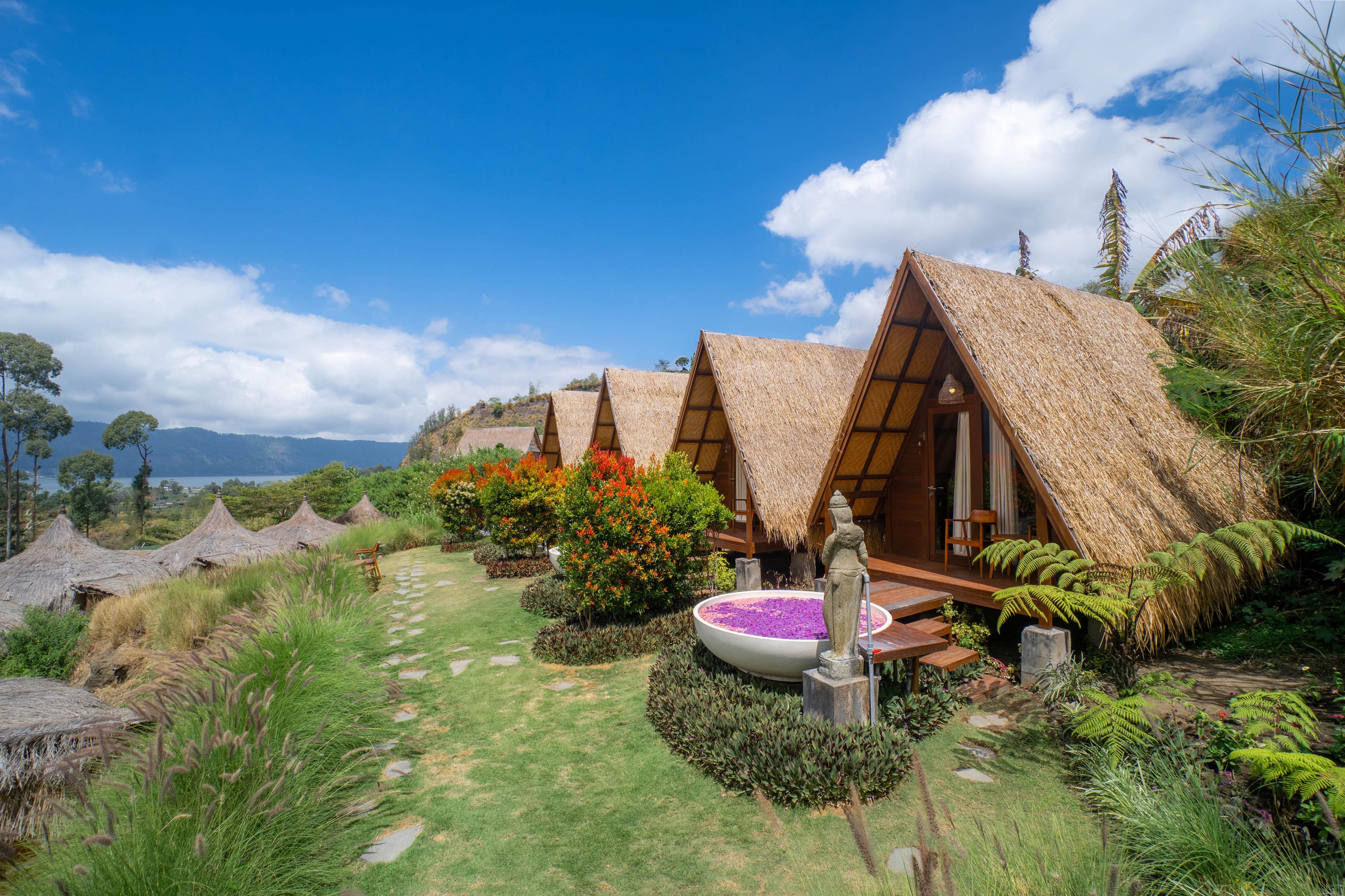 A series of thatched-roof cottages with a garden path leading to a central water feature.