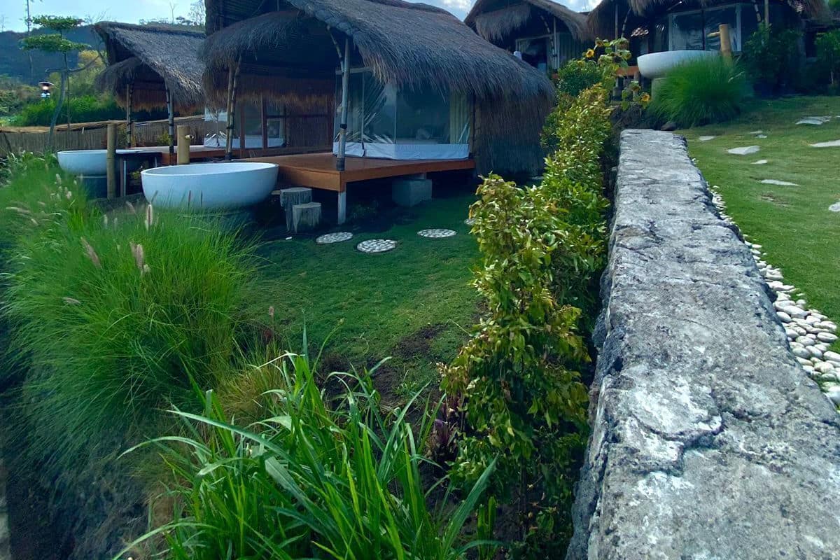 A thatched-roof structure with a wooden deck and a large white basin.