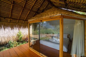 A room with a glass enclosure, wooden flooring, and a thatched roof. - Segara Camp Kintamani (Kintamani)