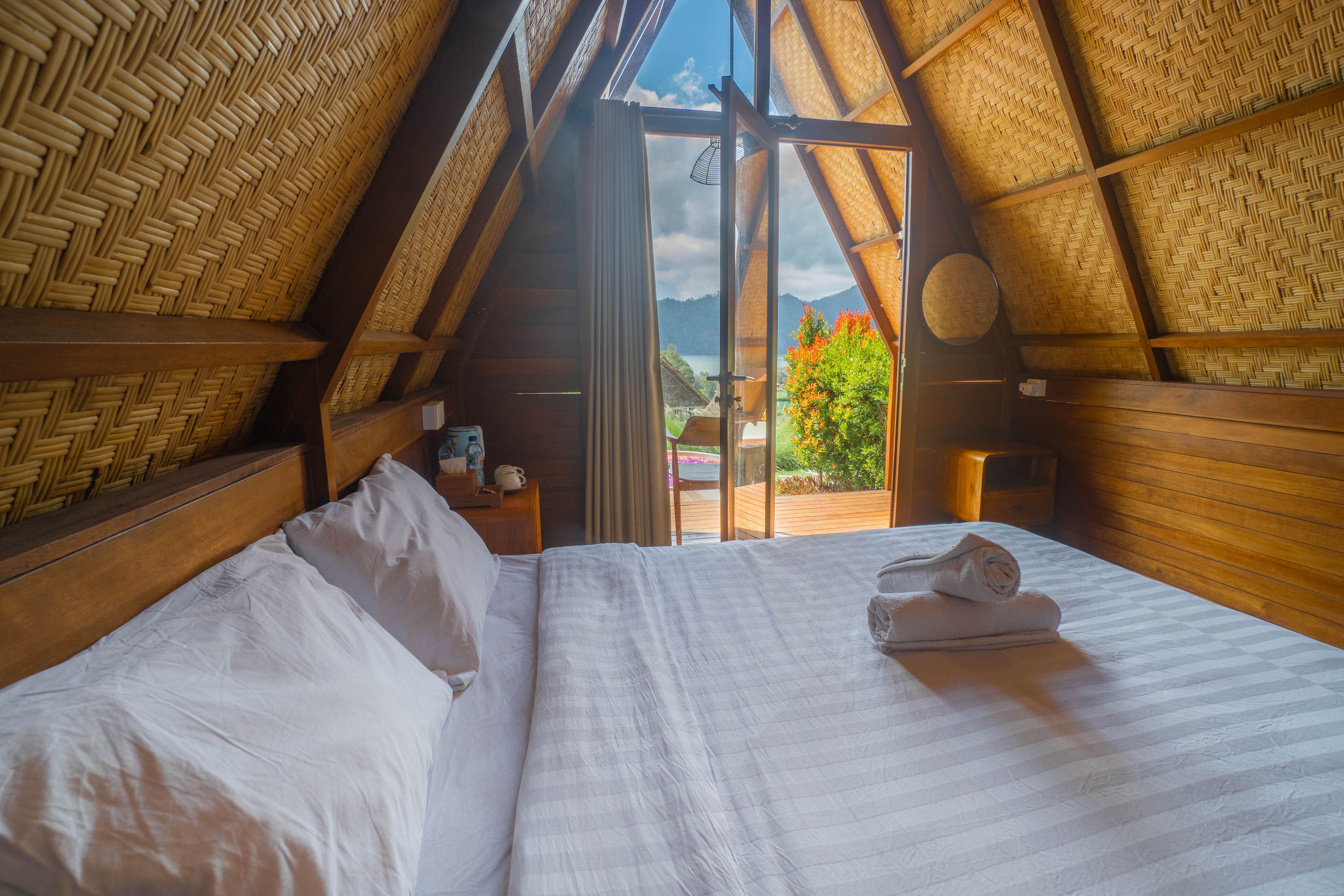 A room with a bed, a window, and a view of the outdoors.
