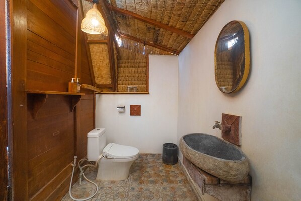 A bathroom with a toilet, a sink, a mirror, and a shower. - Segara Camp Kintamani (Kintamani)