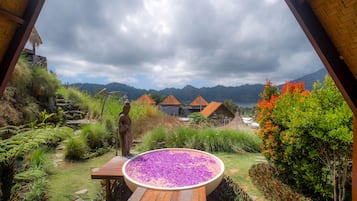 A garden with a wooden deck, a statue, and a large flower bed.