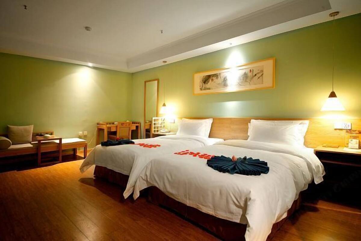 A hotel room with two beds, a desk, a chair, and a bedside table.