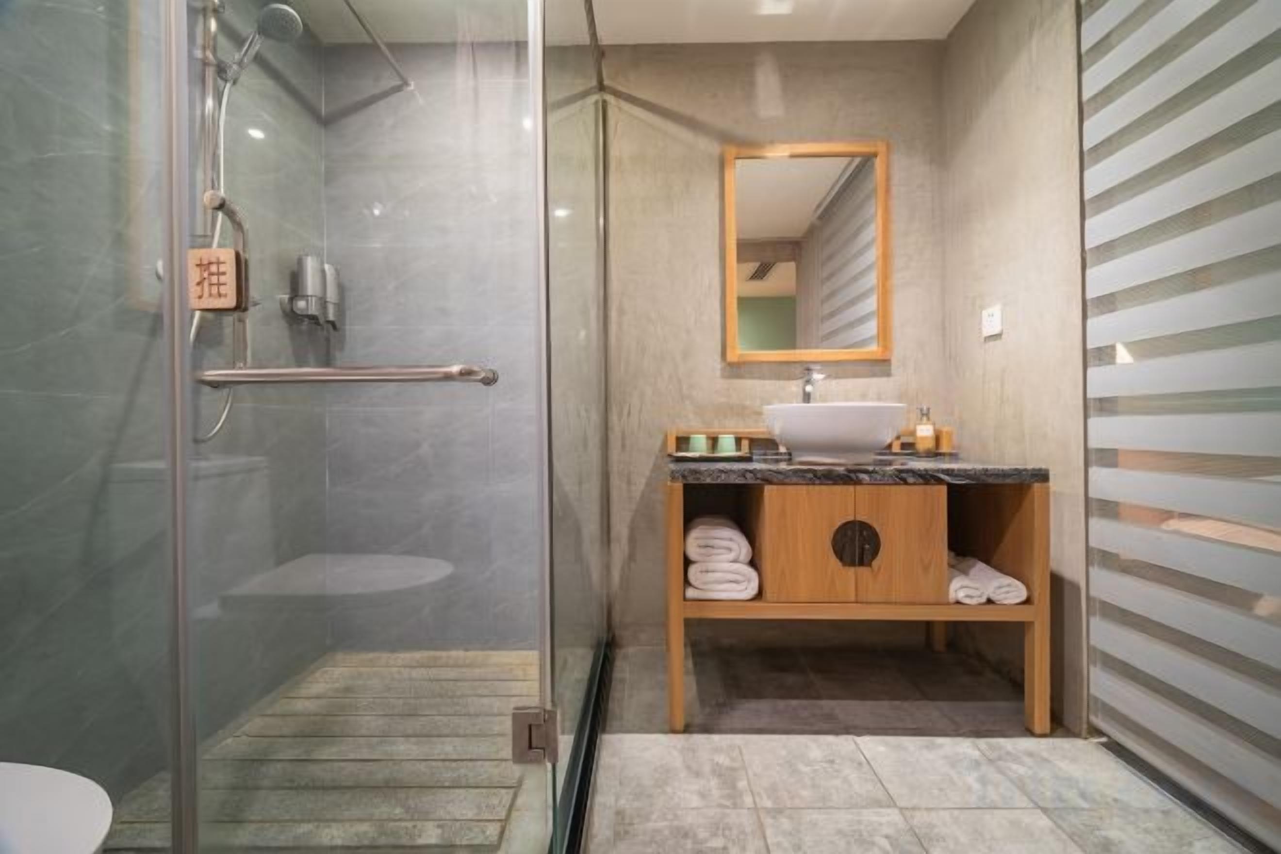 A modern bathroom with a glass-enclosed shower, a wooden vanity with a sink, and a mirror above the vanity.