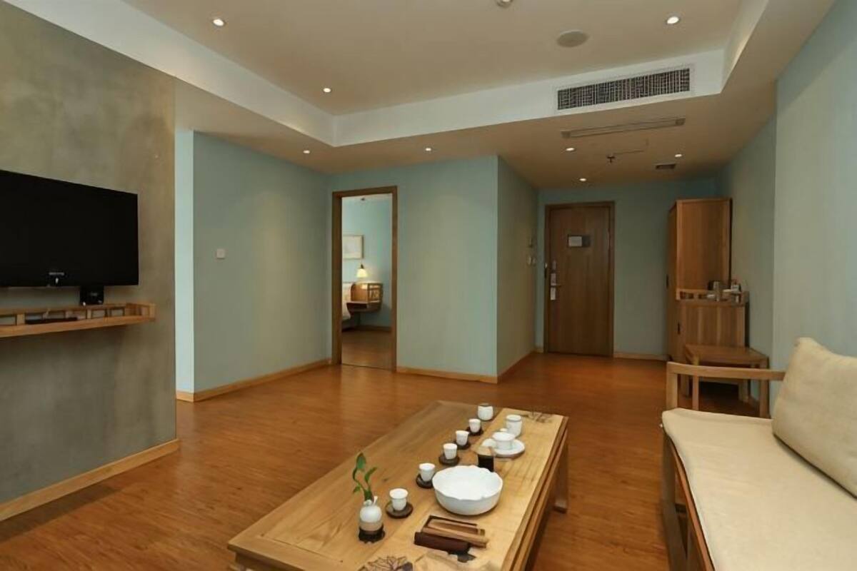 A spacious living room with a wooden coffee table, a flat-screen TV, and a sofa.