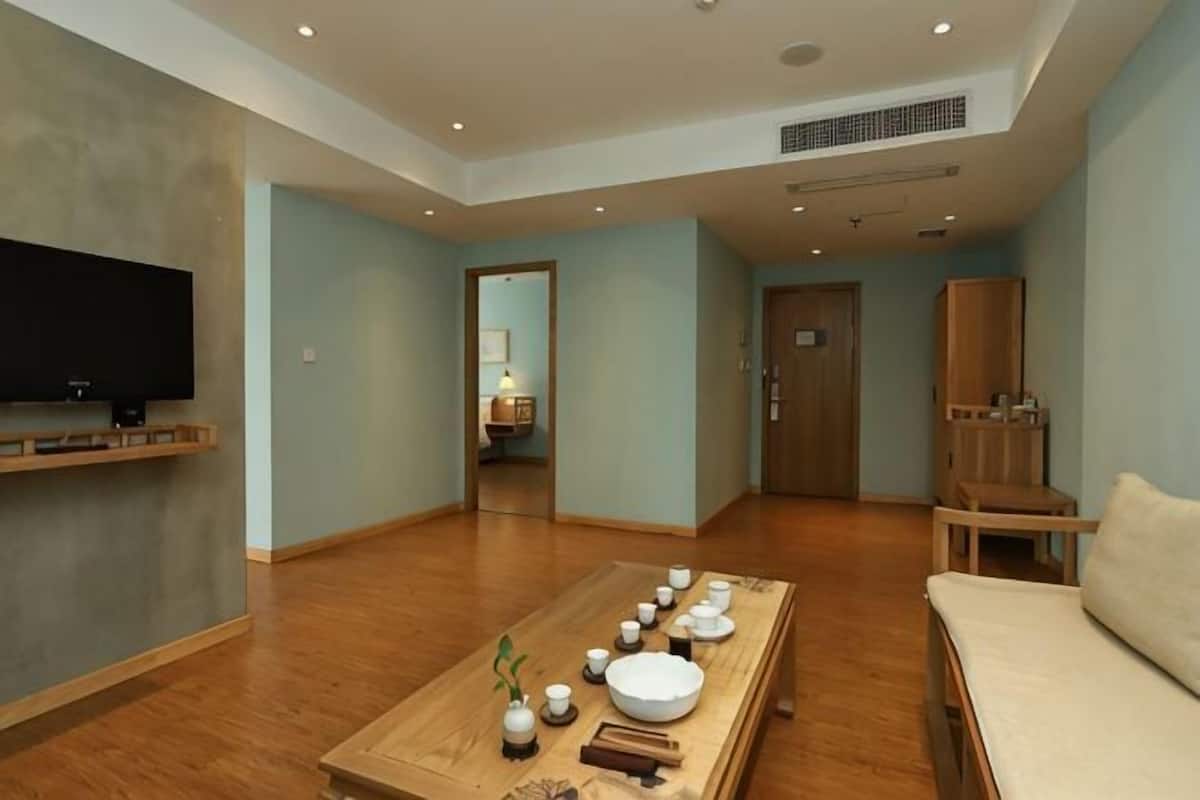 A spacious living room with a wooden coffee table, a flat-screen TV, and a sofa.