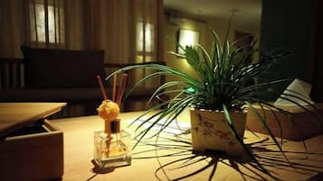 Une table en bois, sur laquelle se trouvent une petite bouteille en verre, une plante en pot et une bougie.