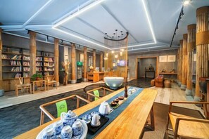 Una biblioteca moderna con estanterías, una larga mesa de madera con teteras y una gran escultura esférica.