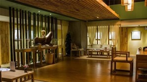 A spacious room with wooden flooring, a sofa set, a dining table, and a decorative Buddha statue. - NengHui Star Hotel (Guiyang)