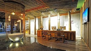 A modern reception area with a wooden reception desk, several chairs, and a unique ceiling design. - NengHui Star Hotel (Guiyang)