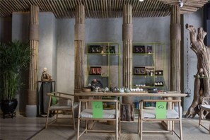 A room with a bamboo ceiling, green-framed shelves, and a central table with chairs. - NengHui Star Hotel (Guiyang)