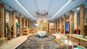 A modern hotel lobby with a central circular seating area, wooden columns, and a large television screen. - NengHui Star Hotel (Guiyang)