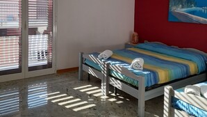 Quarto com cama, ventilador de teto, um quadro e porta de correr de vidro.