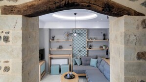 En hyggelig stue med stenvægge, en træbjælke i loftet og en moderne sofa.