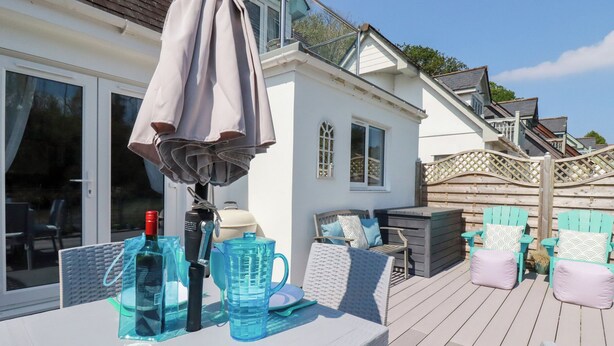Una terraza con mobiliario exterior, una mesa con bebidas y un parasol.