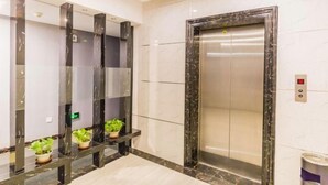 An elevator with a marble finish, a control panel, and potted plants on the wall. - Yasidun Hotel (Hohhot Convention and Exhibition Center) (Hohhot)