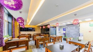 A restaurant with wooden tables and chairs, purple decorative elements, and a flat-screen TV on the wall. - Yasidun Hotel (Hohhot Convention and Exhibition Center) (Hohhot)