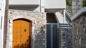 Een modern gebouw met een gevel van natuursteen, een houten deur en een trap die naar een balkon leidt.