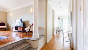 Uma sala de estar espaçosa com piso de madeira, uma escada e vista para a sala de jantar.