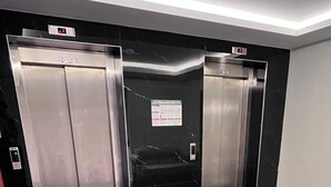 Um elevador moderno com portas metálicas e painel digital.