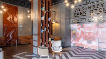 Un moderno vestíbulo con una estantería central, un sillón blanco y un piso con diseño.