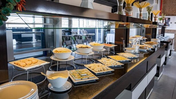 Uma mesa de buffet com diversos alimentos e pratos dispostos em suportes.