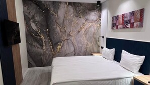 Quarto moderno com cama grande, televisão na parede e luminária no teto.