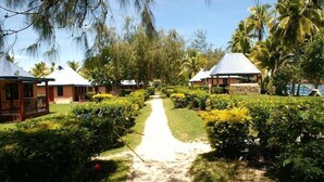 A pathway leading to multiple bungalow-style accommodations surrounded by lush greenery and palm trees. - Nabua Lodge Hidden Getaway (Nacula Island)