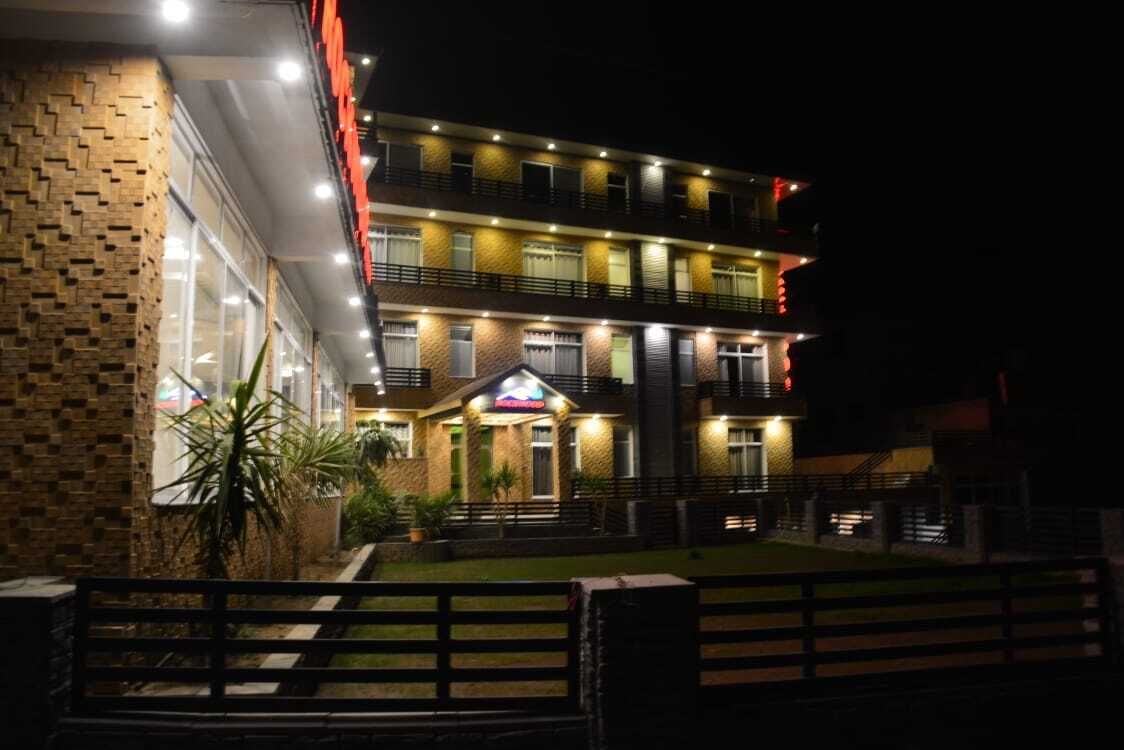 A multi-story hotel with a brick facade, illuminated windows, and a well-lit entrance.