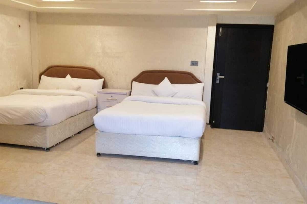Ein Hotelzimmer mit zwei Betten, einem Wandfernseher und einer Tür.