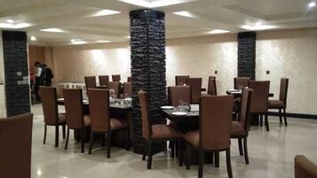 A restaurant with multiple tables and chairs, a stone pillar, and a clean, tiled floor.