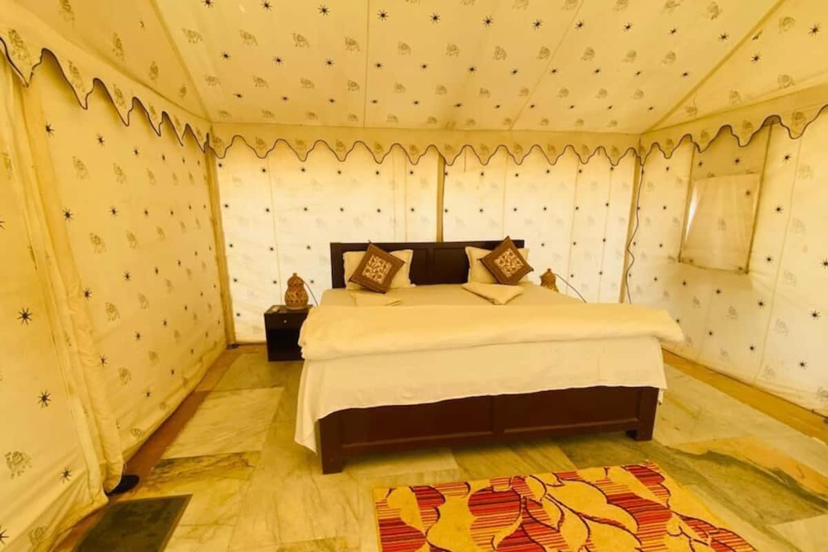 Una habitación con cama, mesitas de noche, alfombra estampada y paredes con diseño de estrellas.