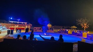 An outdoor nighttime event with a stage, audience, and a pool. - Barna Desert Camp (Jaisalmer)