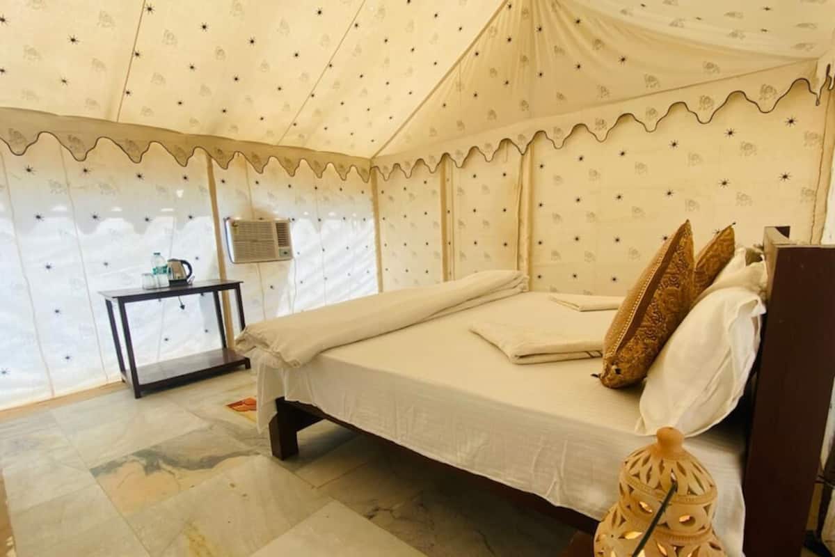 Una habitación con carpa, una cama, una mesita con lámpara y un farol decorativo.