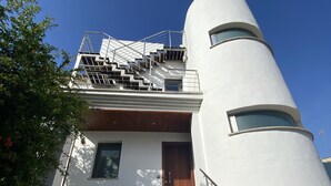 A modern building with a unique cylindrical structure, a wooden door, and a staircase leading to an upper level. - Villa Casa Margarita with sea view (Alcudia)
