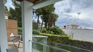 A covered outdoor area with a pool, wicker furniture, and a glass railing overlooking a landscaped garden. - Villa Casa Margarita with sea view (Alcudia)