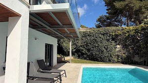 A modern house with a swimming pool, outdoor seating, and a view of trees. - Villa Casa Margarita with sea view (Alcudia)