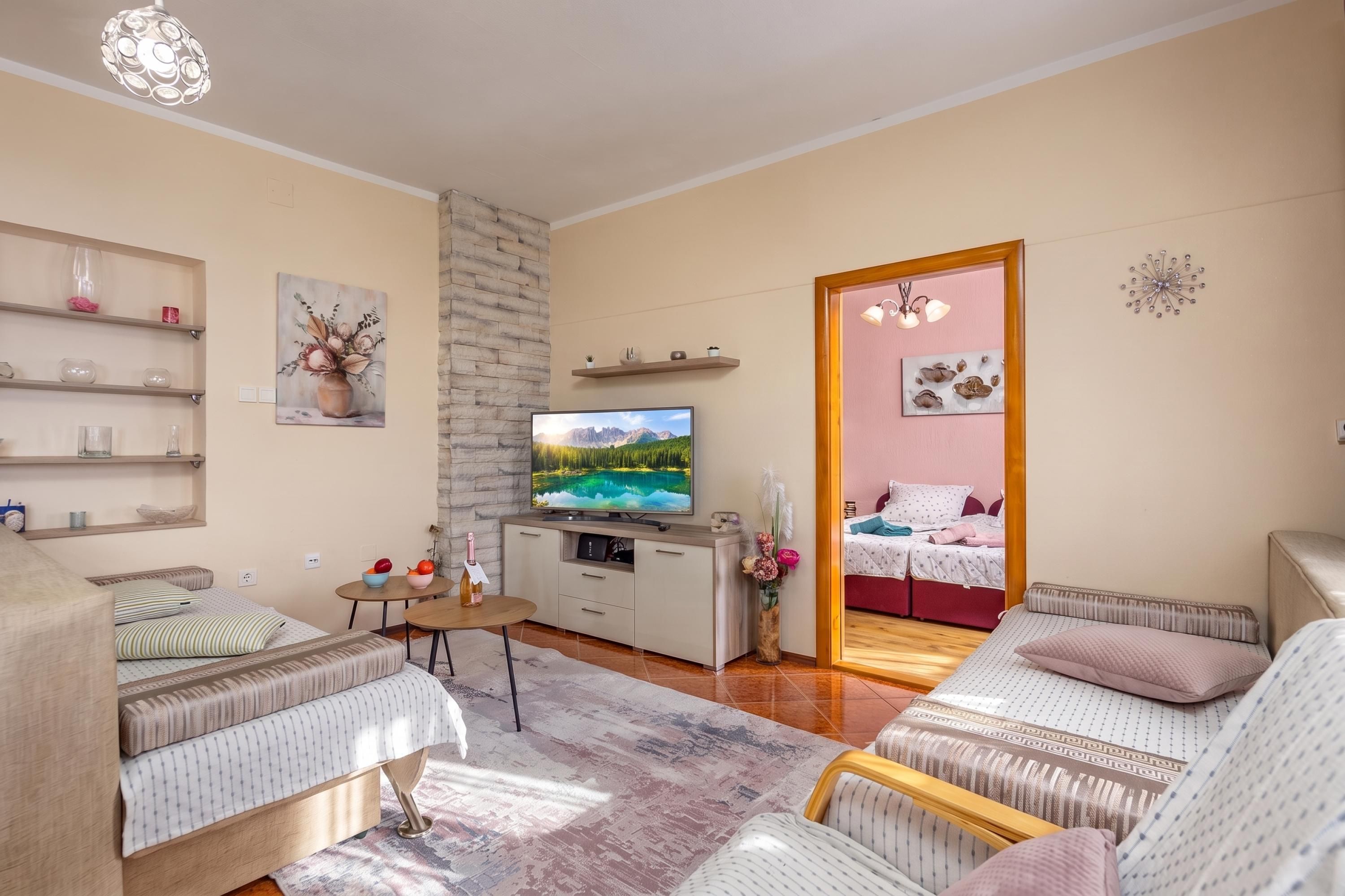 Una sala de estar moderna con un televisor de pantalla plana, una zona de comedor con mesa y sillas, y un dormitorio con cama y mesita de noche.