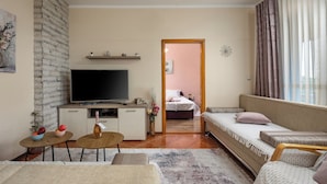 A modern living room with a flat-screen TV, a sofa, a small table, and a decorative vase. - Kostrena Apartment Maja (Kostrena)